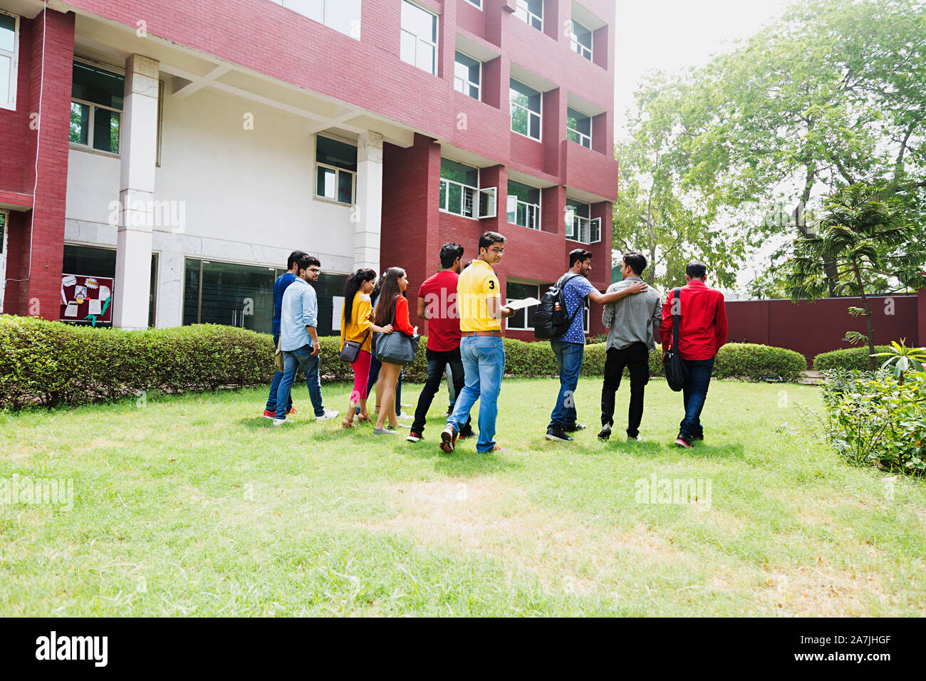 Groupe de jeunes garçons et filles du Collège Walking-Together In-Outside Carnet d'amis avec Campus University Building Banque D'Images