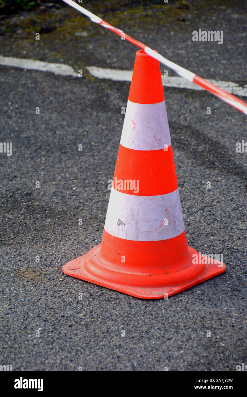 Gros plan sur un cône de circulation blanc orange avec ruban rouge-blanc à un site de construction de la rue, le trafic sur le cône de sécurité pour les gens de la rue Banque D'Images