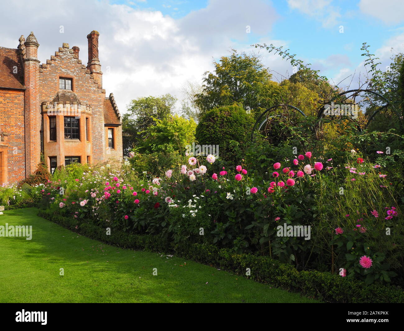 Chenies Manor House face sud ouest, encadrée par les frontières des paniers avec Dahlia rose coloré et variétés Cosmos sur une belle soirée de septembre. Banque D'Images