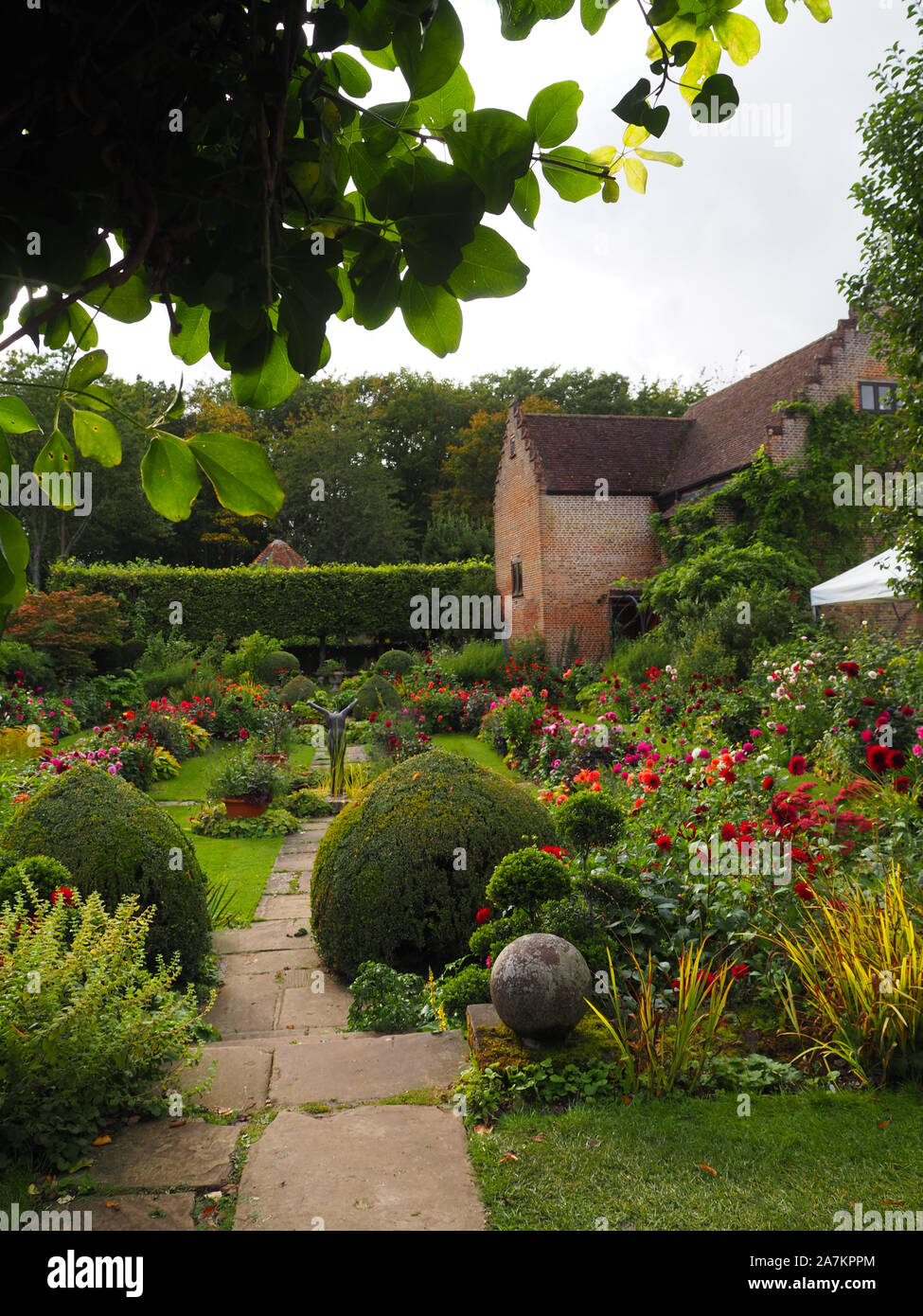 Vue à travers la serrure Akebia vigne au jardin en contrebas à Chenies Manor à Dahlia. La voie de la terrasse avec jardin et la construction du pavillon. Banque D'Images