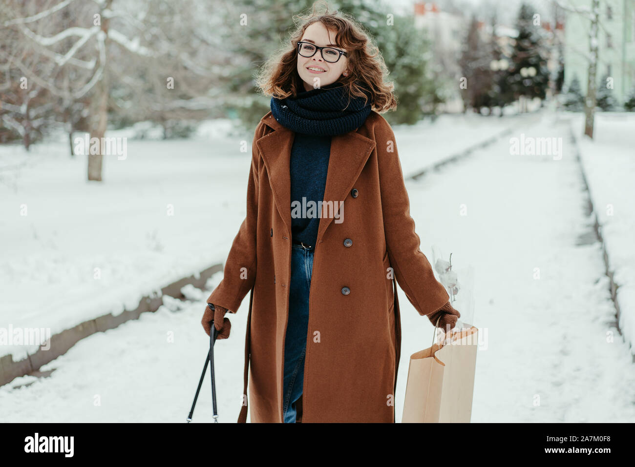 Belle jeune femme au foulard tricoté debout dans le parc avec votre panier. La mode d'hiver Banque D'Images