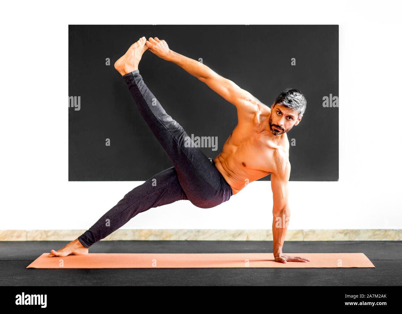 Man doing yoga étirement et d'équilibre pour la mobilité et renforcer ses muscles dans une salle de sport dans un concept de santé et de remise en forme Banque D'Images