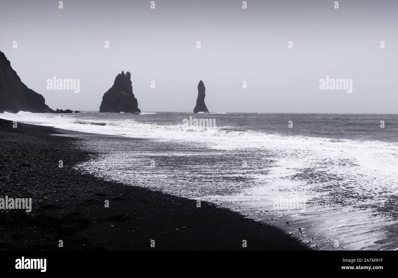 Paysage spectaculaire de la plage de sable noir de Reynisfjara qui jouit de l'Islande sur un jour nuageux Banque D'Images