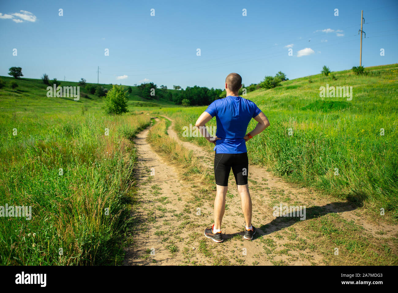 Homme debout avant de démarrer exécuter runner on rural road Banque D'Images