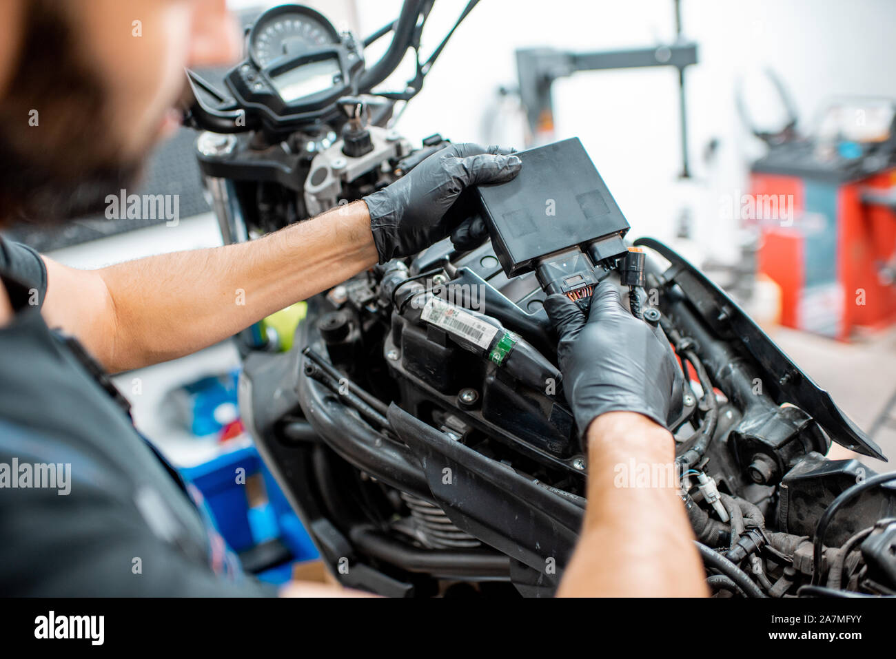 Electricien ou réparateur à gants de protection de câblage de liaison dans la moto lors d'une réparation à l'atelier, close-up Banque D'Images