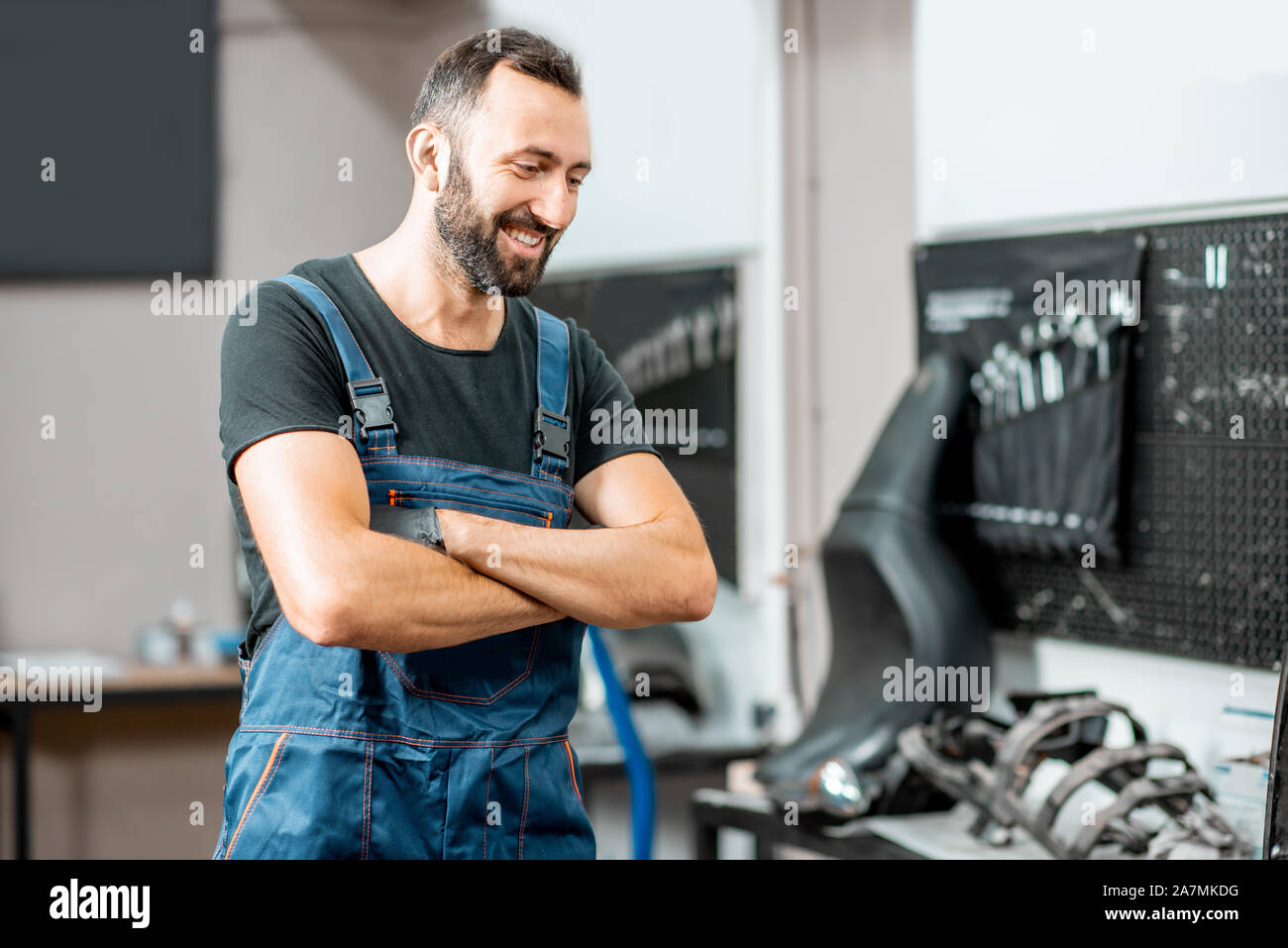 Portrait of a handsome cheerful en salopettes de travail à l'atelier de réparation de motos Banque D'Images