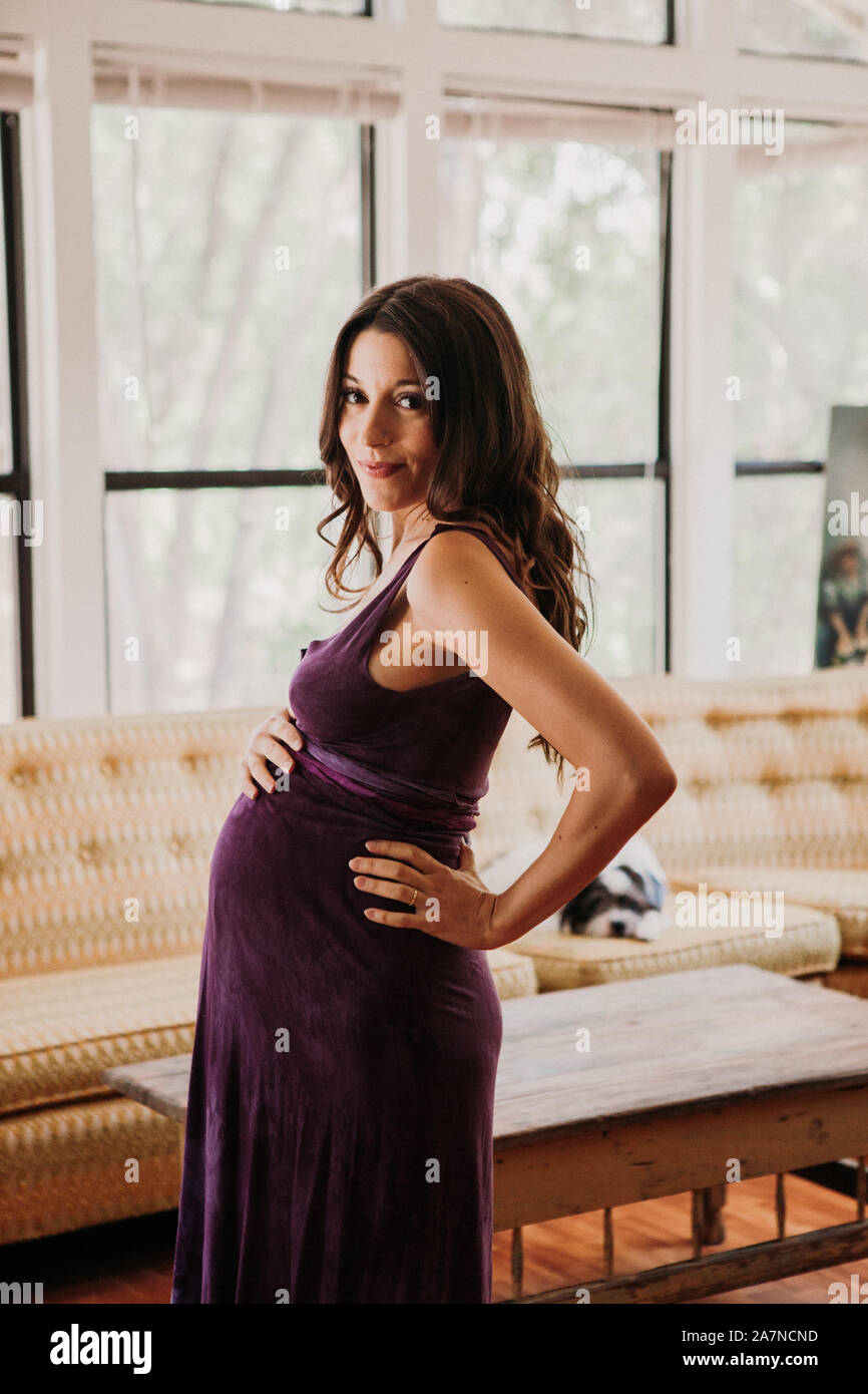 Femme enceinte se tient dans sa salle de séjour Banque D'Images
