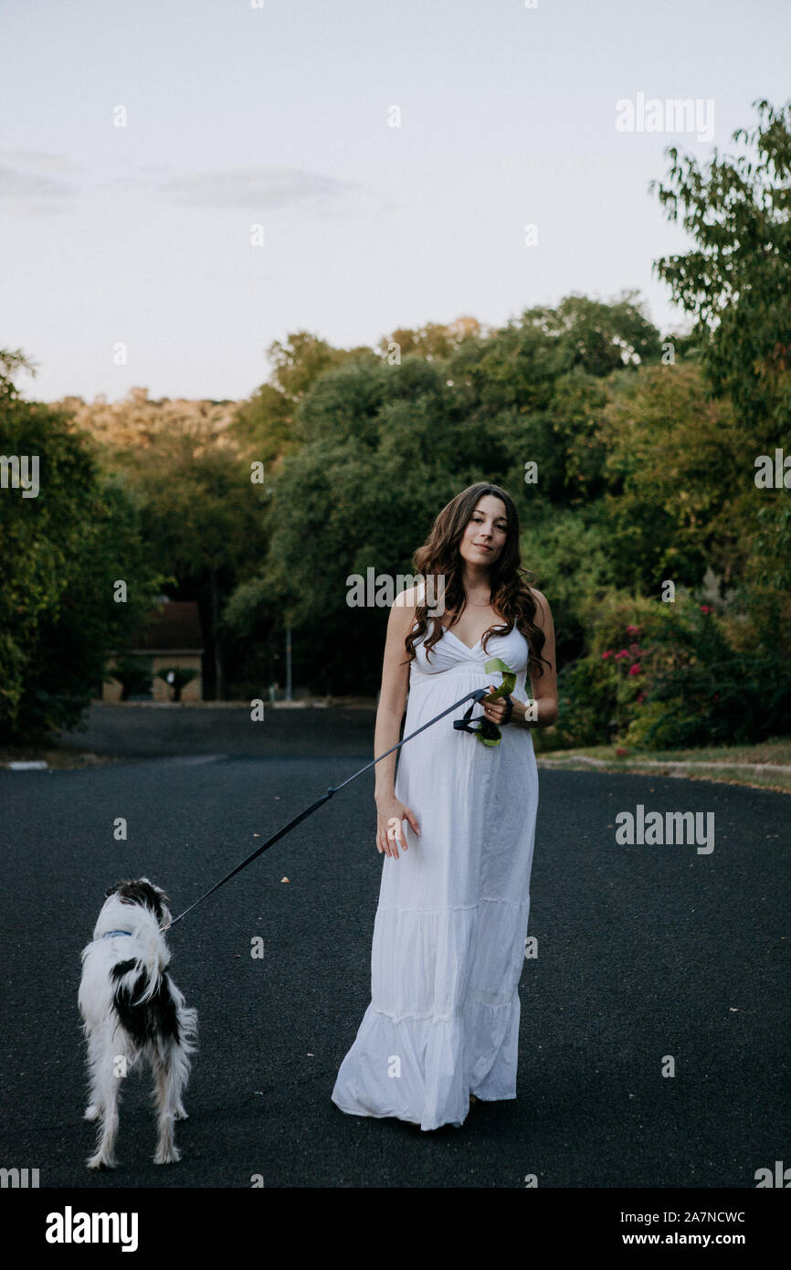 Femme enceinte robe blanche promener son chien Banque D'Images