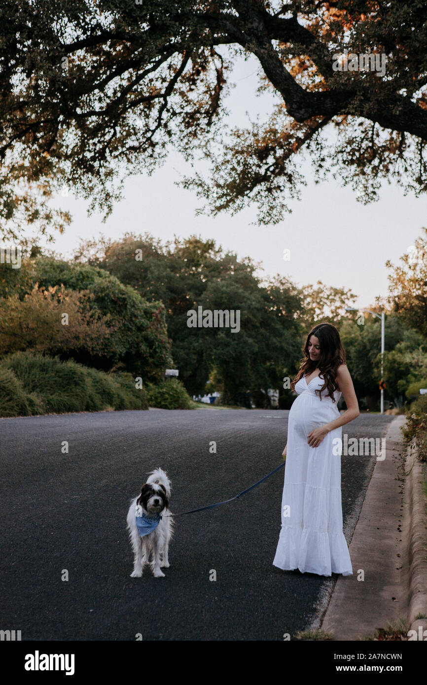Femme enceinte robe blanche promener son chien Banque D'Images