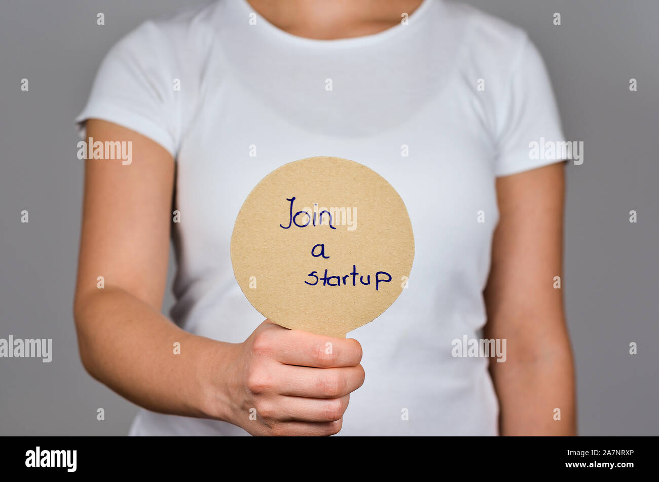 Les jeunes femmes montrant papier carton rond, avec le texte en bleu - Inscrivez-vous d'une startup. Banque D'Images
