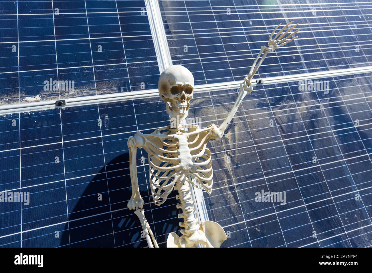 Le skeleton se penchant sur des panneaux solaires dans le désert Banque D'Images