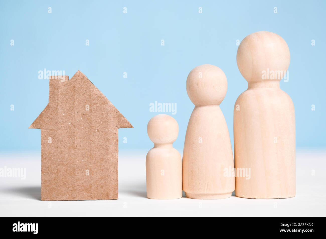 Figures en bois famille avec découpe carton house sur fond bleu. Concept de déménagement au nouveau domicile, l'établissement, de vélos, d'hypothèque, de l'expulsion. Banque D'Images