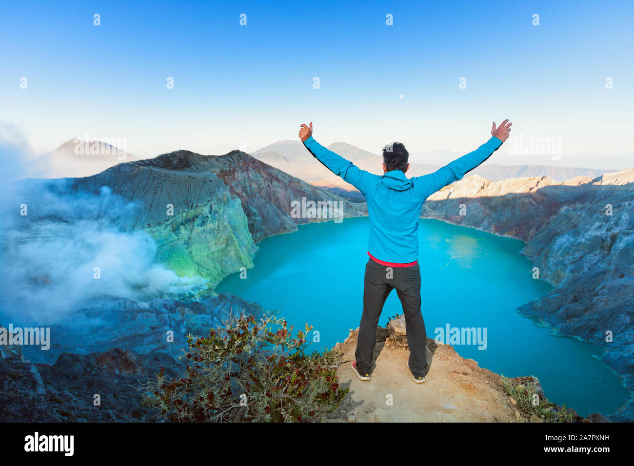 Homme debout au lever du soleil sur le volcan Kawah Ijen rocher au-dessus de cratère. Voir plus grand monde dans le lac acide de soufre. Destination populaire, randonnée aventure. Banque D'Images