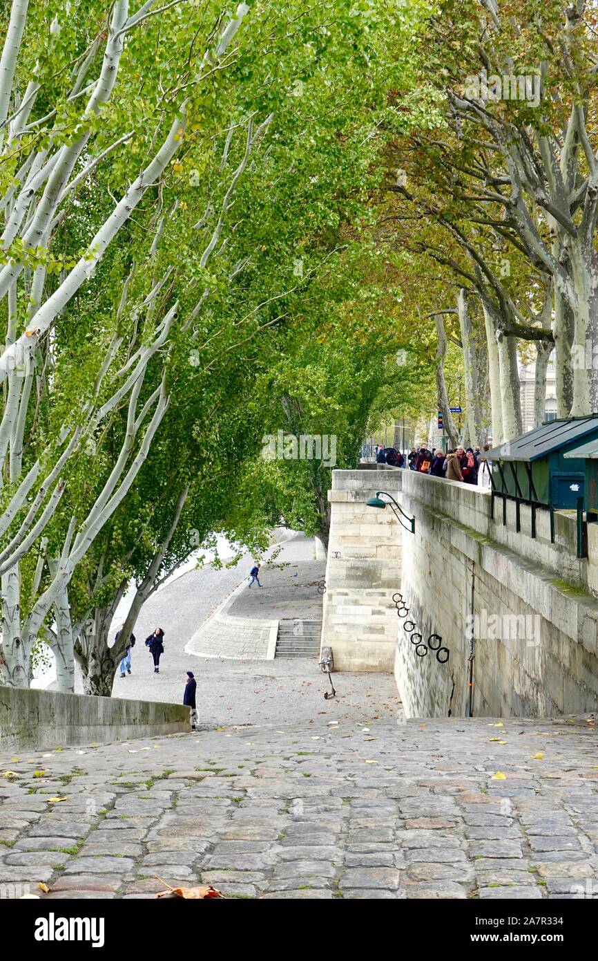 Les gens qui marchent, portant des vêtements d'automne, le long de la partie supérieure et inférieure quai du Louvre le long de la Seine avec boîtes bouquinist vert, Paris, France. Banque D'Images
