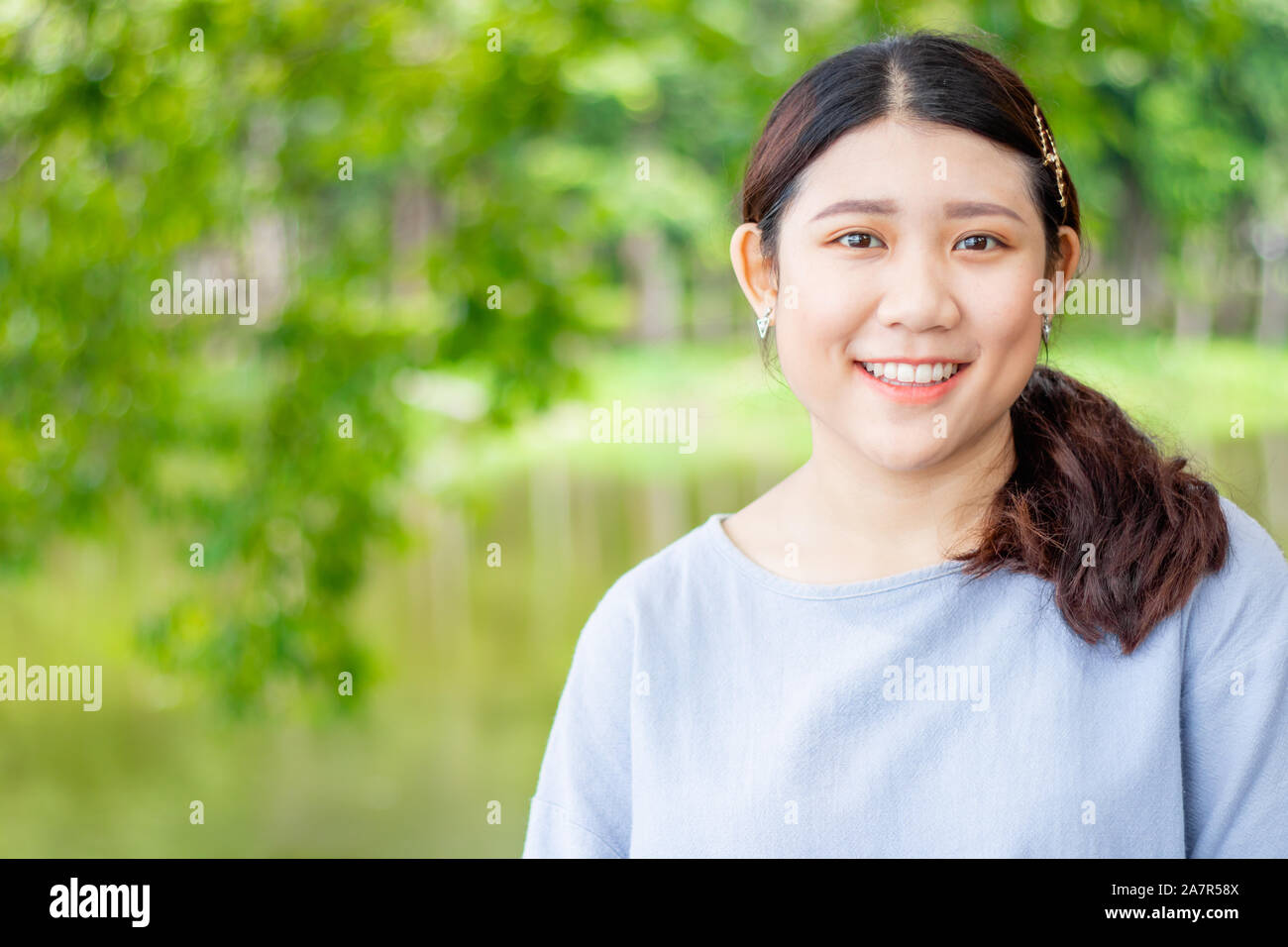 Image ado asiatique unique cute girl smiling green nature plein air avec de l'espace pour le texte. Banque D'Images