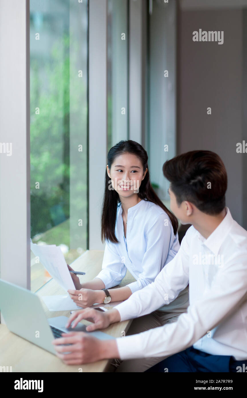 Jusqu'à la taille de deux coup de jeune homme et femme d'affaires aux cheveux noirs parlant ensemble tout en travaillant à un bureau dans un bureau Banque D'Images