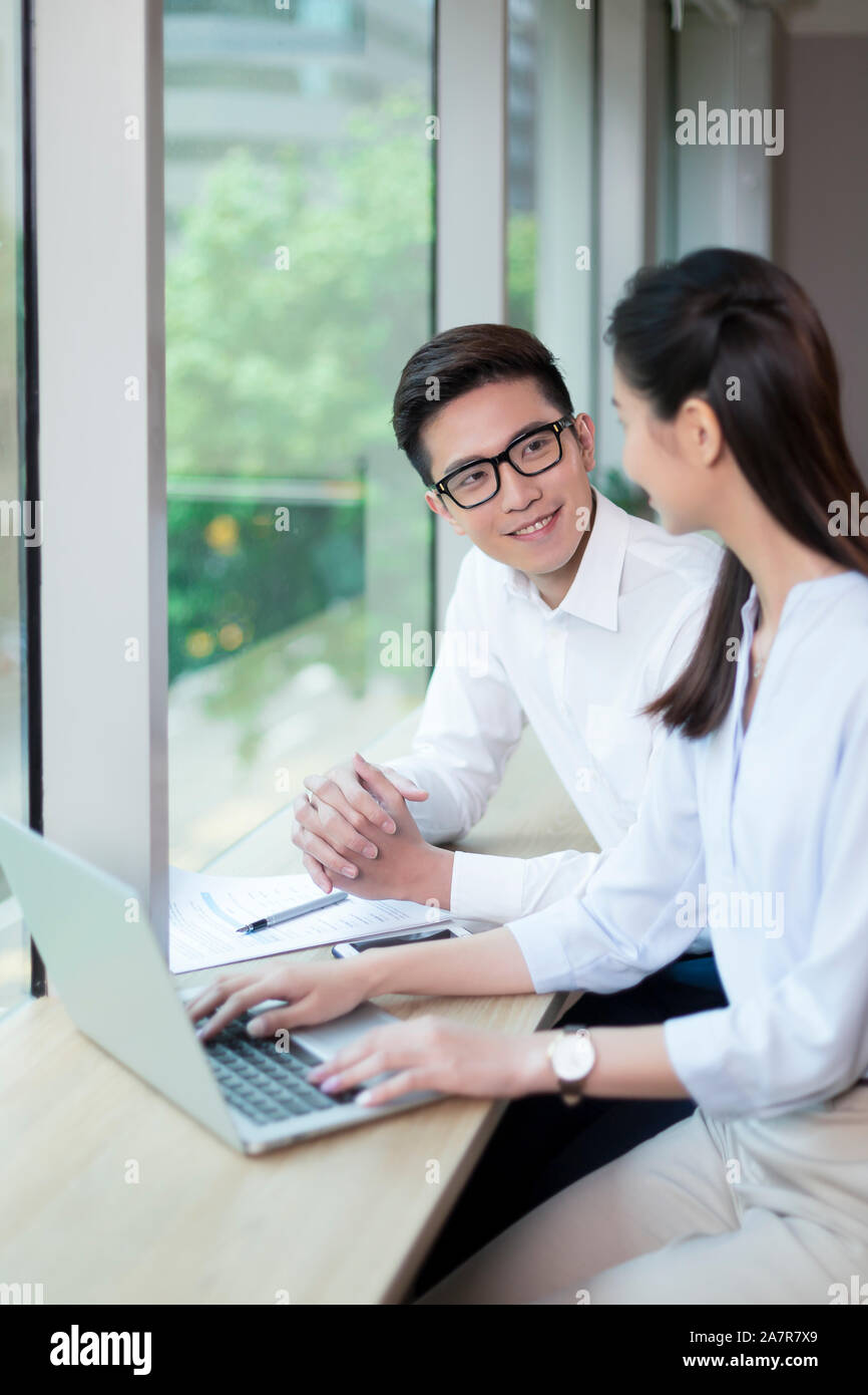 Jusqu'à la taille de deux coup de jeune homme et femme d'affaires aux cheveux noirs parlant ensemble tout en travaillant à un bureau dans un bureau Banque D'Images