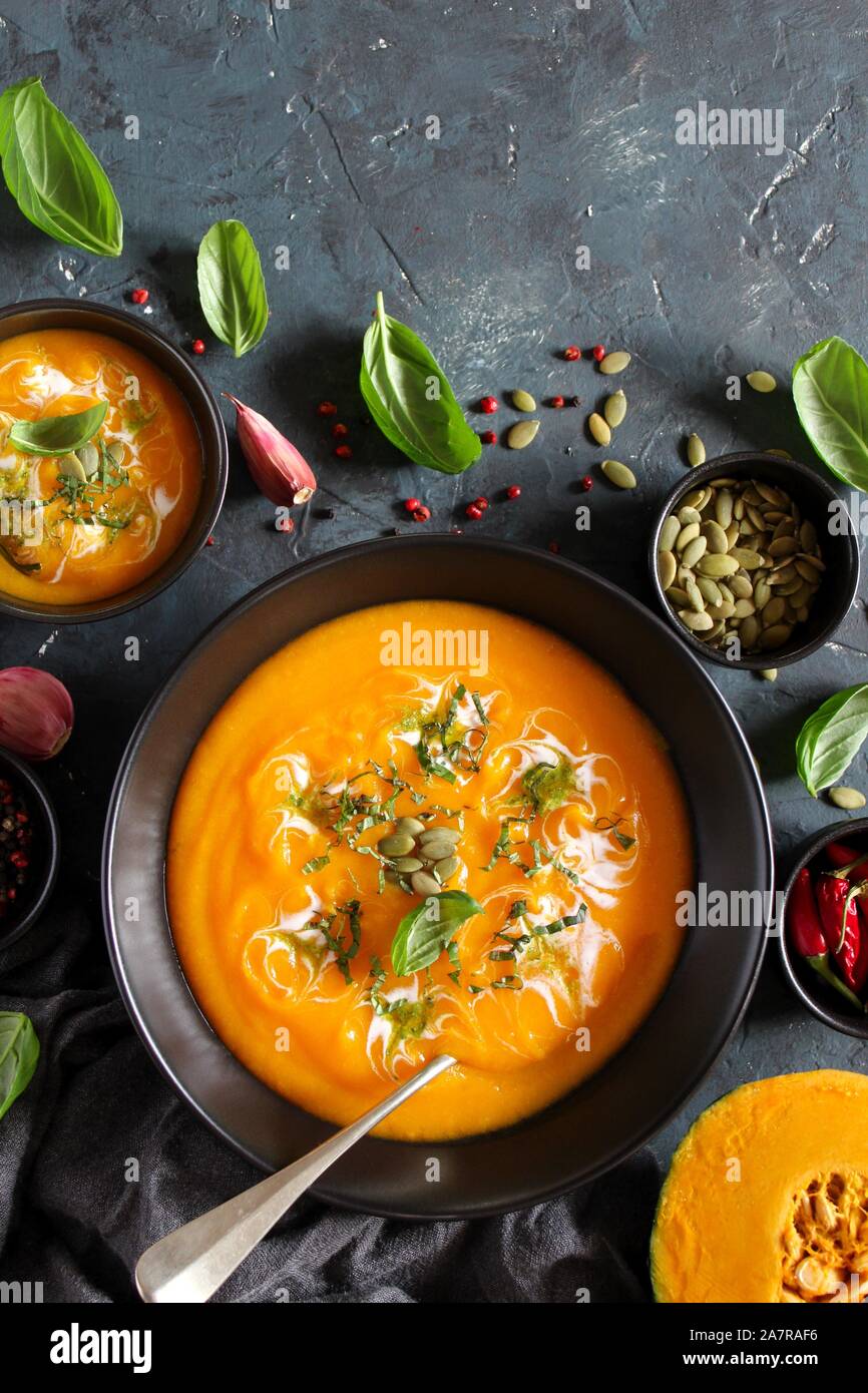 Soupe de carottes et de potiron à la crème et le basilic sur fond sombre. Vue de dessus avec l'exemplaire de l'espace. Banque D'Images