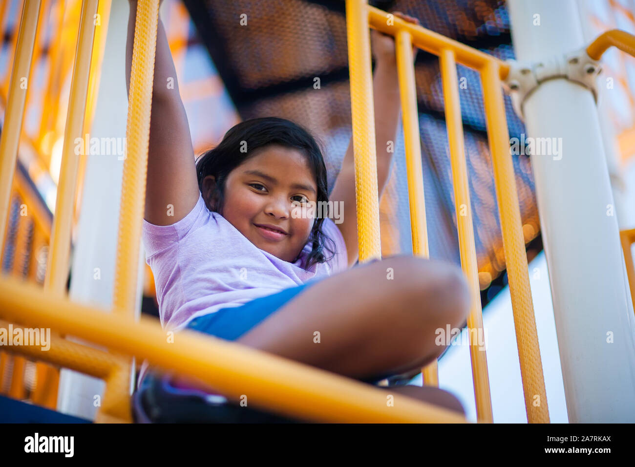 Une jeune fille accrochée à la barre dans une jungle de sport ou de jeux pour les enfants. Banque D'Images