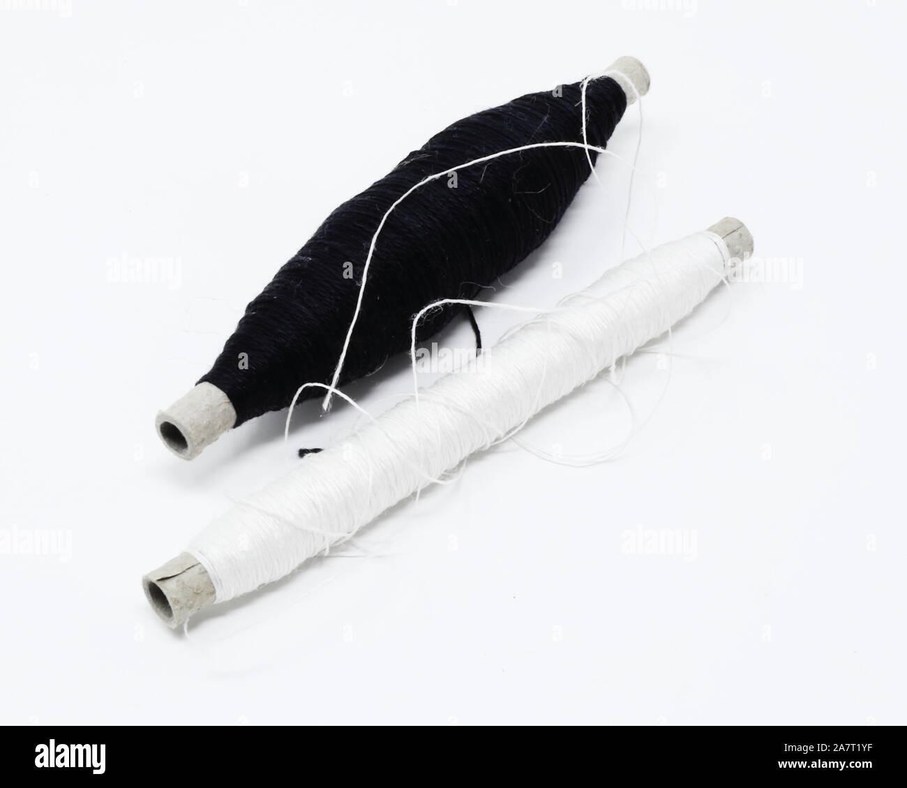 Deux douilles de tissage/perçons partiellement rempli de noir et blanc de fils de coton mercerisé Banque D'Images