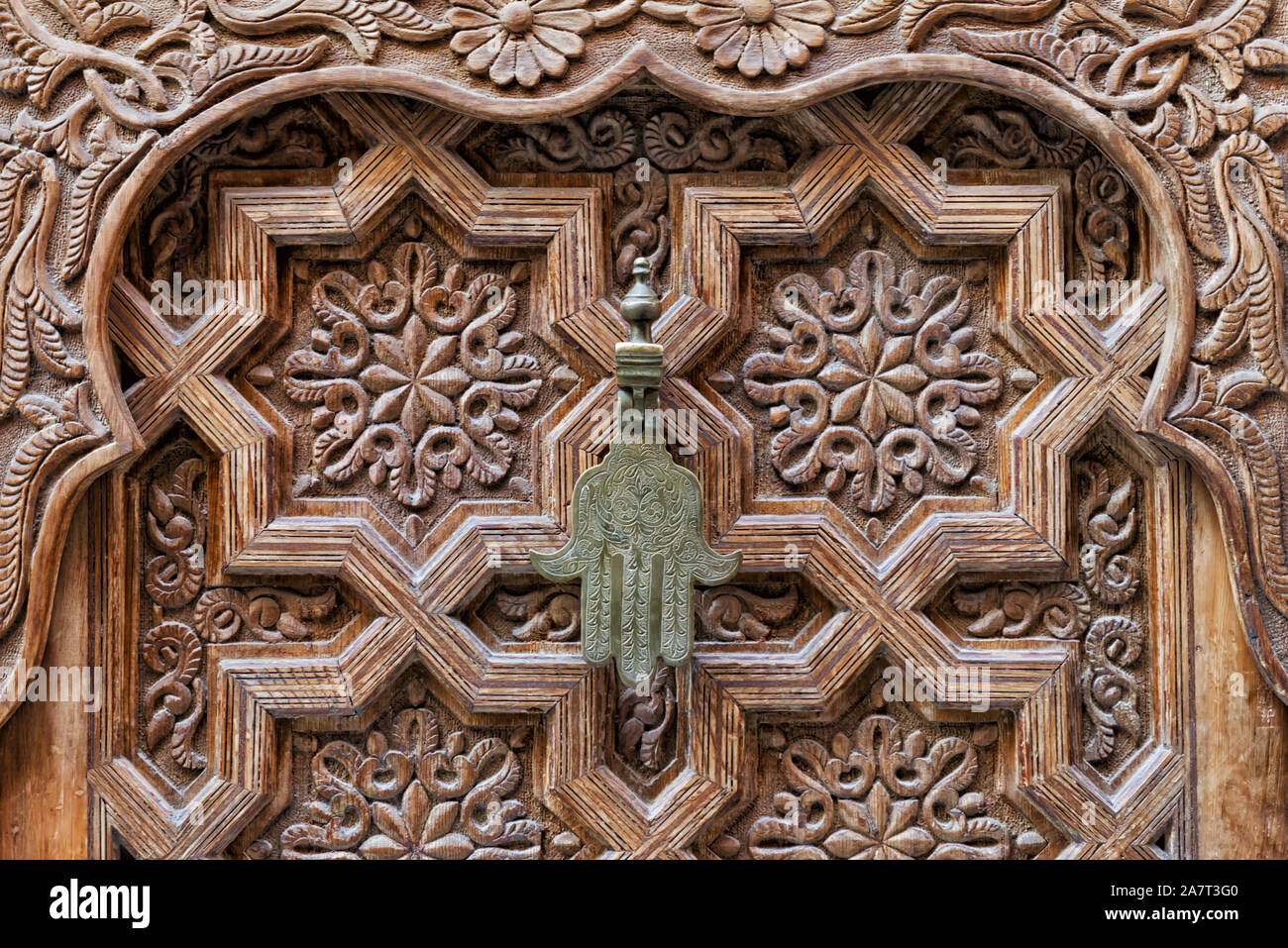 Poignée de porte en fer de la "Main de Fatima" sur un sol en bois, porte marocaine dans la médina de Marrakech, Maroc. Banque D'Images