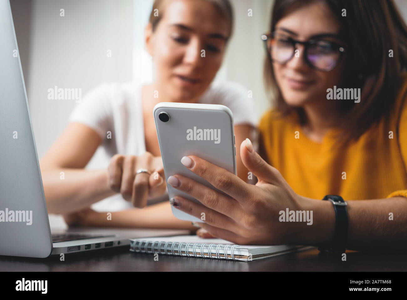 Deux jeunes beau business woman using smartphone à son lieu de travail en bureau. De l'équipe féminine positive manager avec laptope et téléphone Banque D'Images