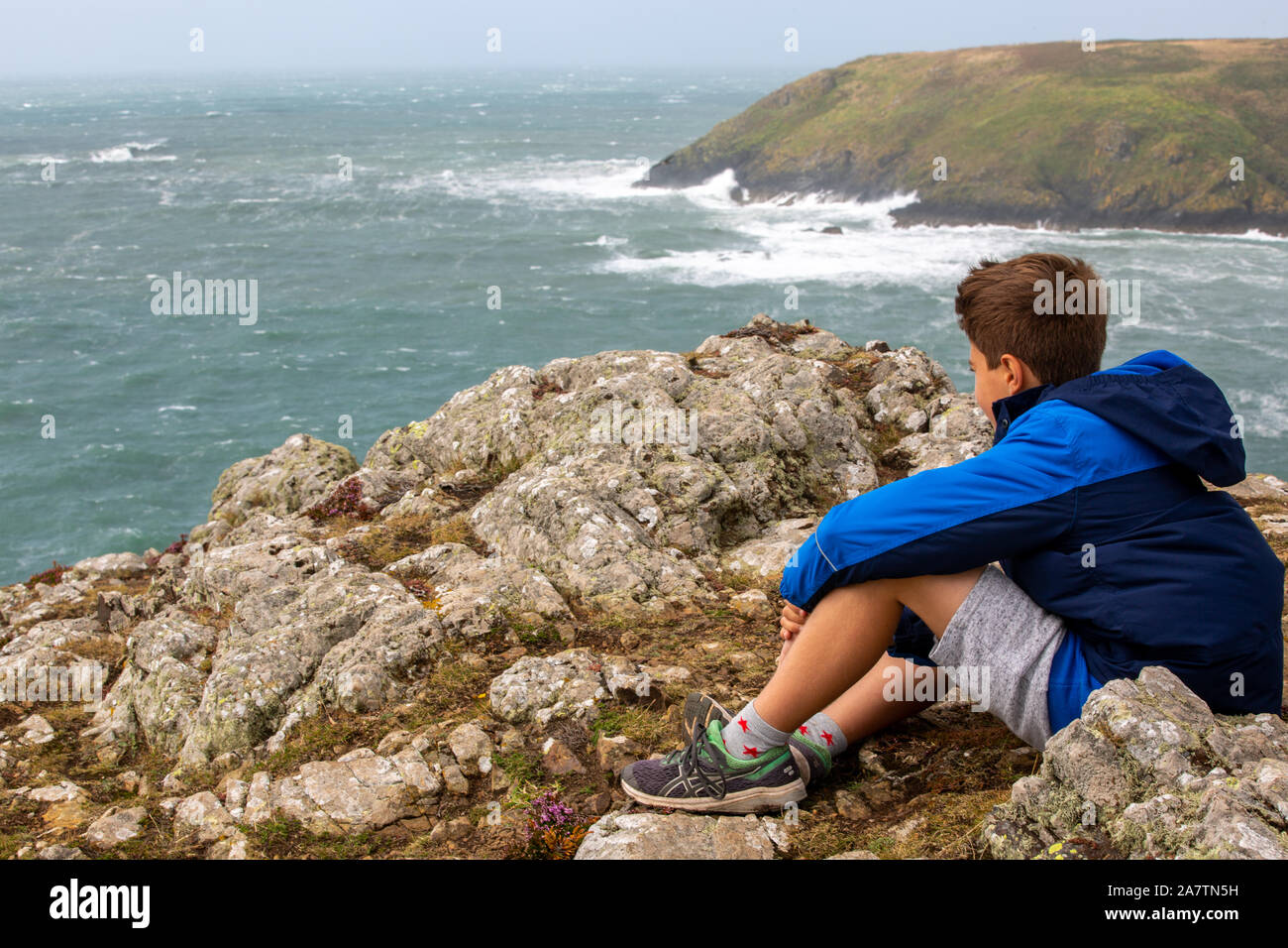 Aa garçon de 11 ans à la recherche sur la vue sur la mer de Deer Park, Pembrokeshire, Pays de Galles. Banque D'Images