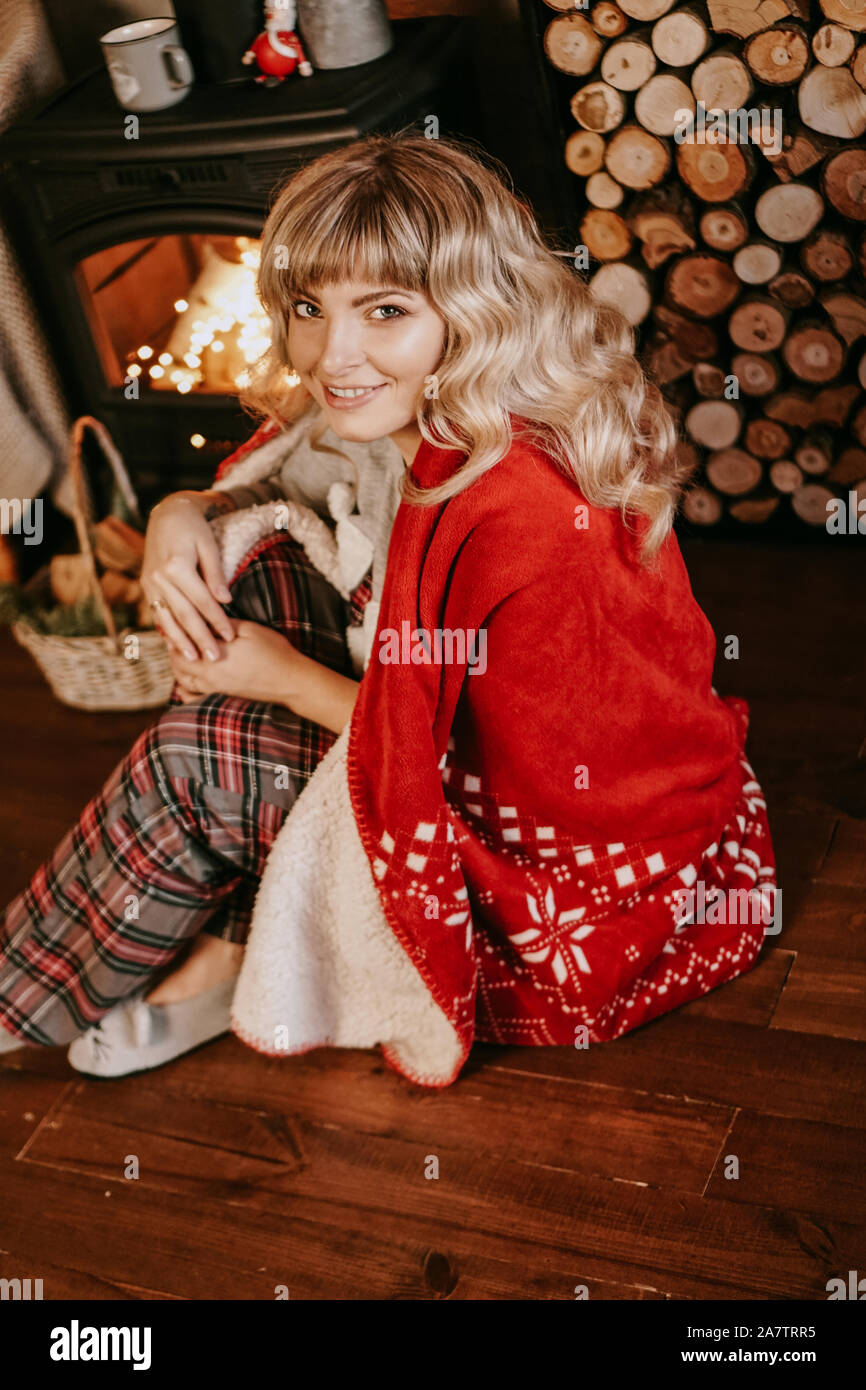 Une belle jeune femme dans un plaid rouge se trouve dans un cadre chaleureux de l'intérieur Nouvel An classique Banque D'Images