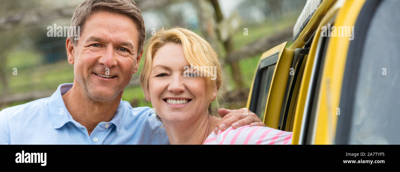 Vue panoramique portrait d'une belle réussite et heureux homme femme couple d'âge moyen rire ensemble par un bus en camping-car. Bannière web Panorama Banque D'Images