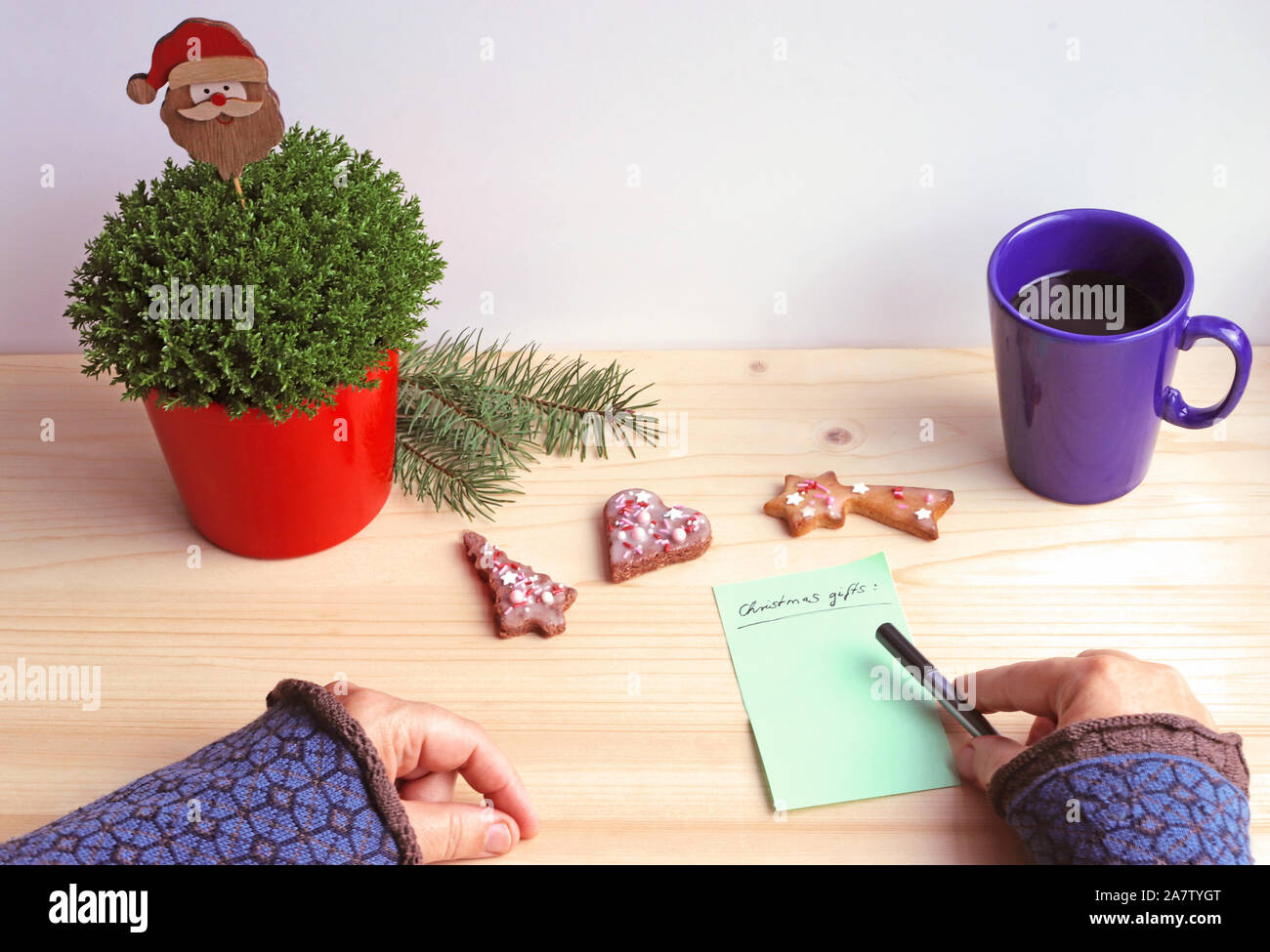 Mains d'une femme écrit une liste de cadeaux de Noël sur une table avec des  biscuits de Noël, branches d'épinette et un père noël Photo Stock - Alamy