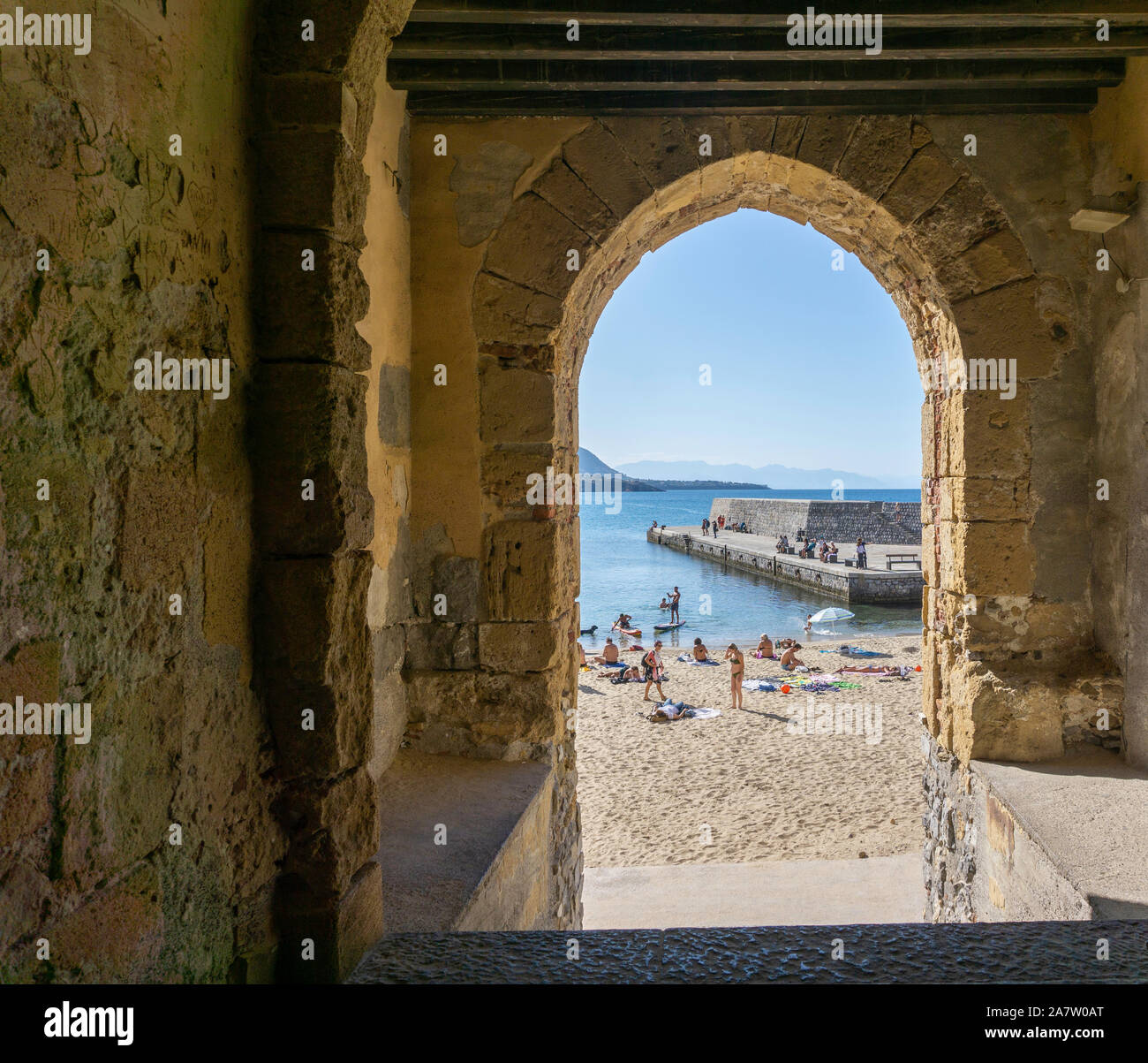 La plage et la jetée de Cefalú, Sicile, Italie, vu par une arcades. Banque D'Images