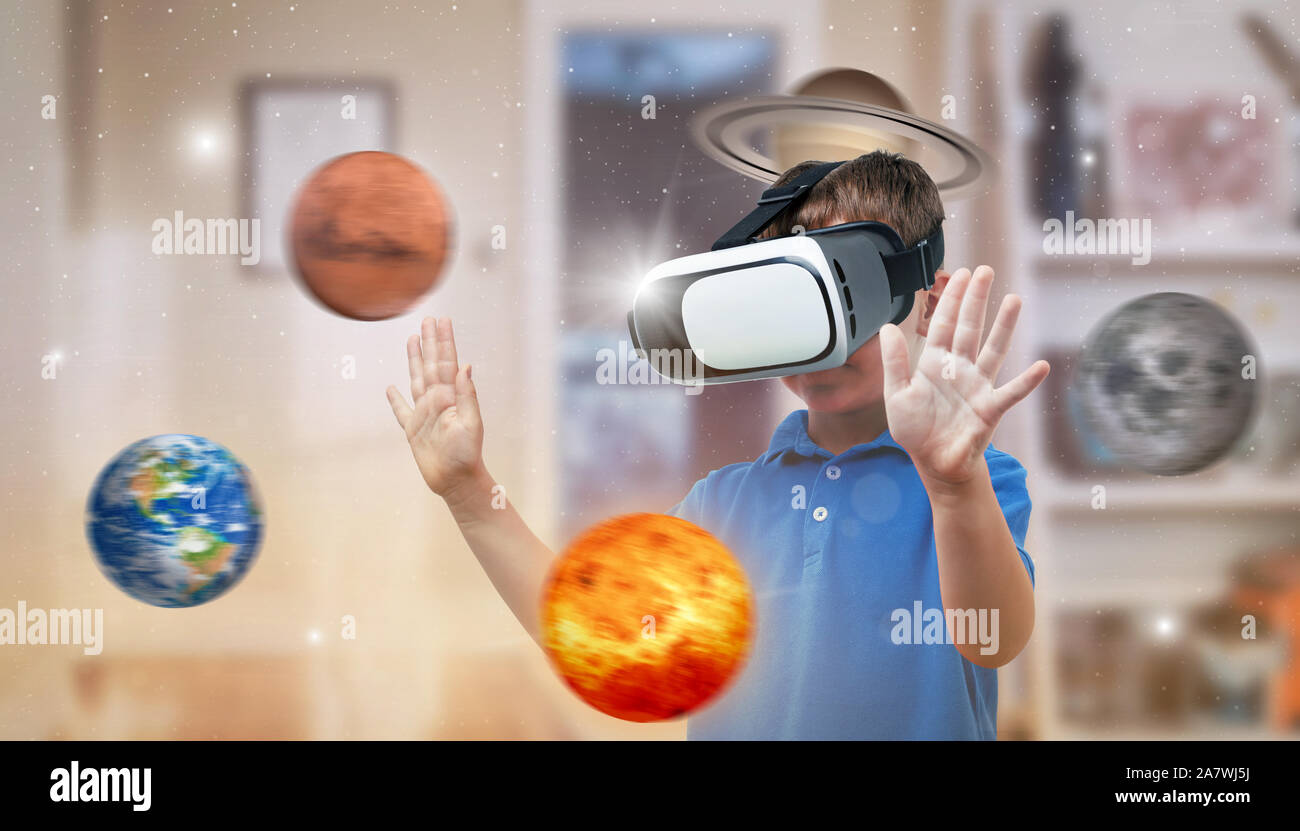 Garçon avec un casque de réalité virtuelle l'exploration de planètes dans sa chambre. Le concept d'utiliser les technologies modernes de l'éducation. Banque D'Images