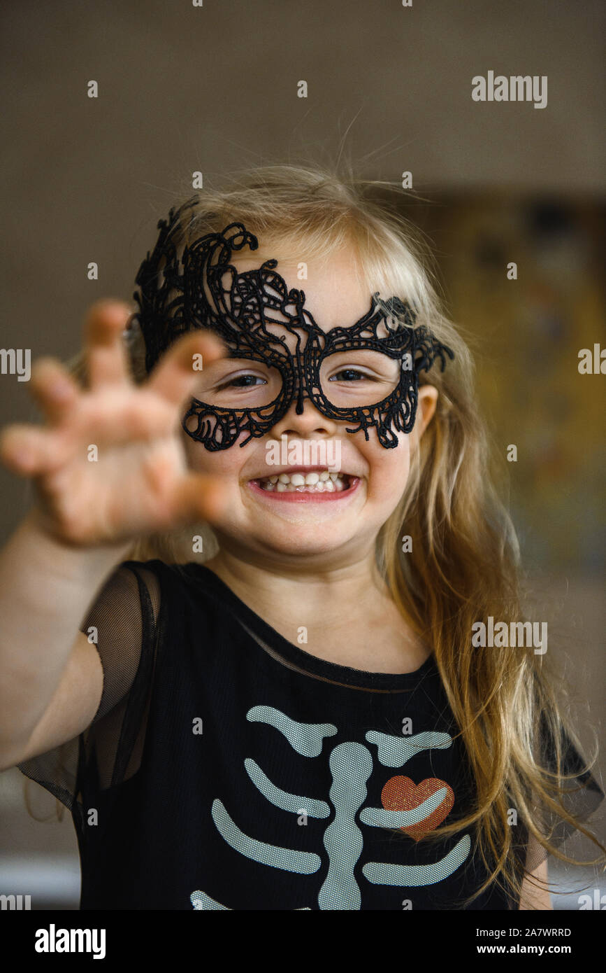 Little Smiling Girl in mask habillés pour Halloween en costume de squelette Banque D'Images