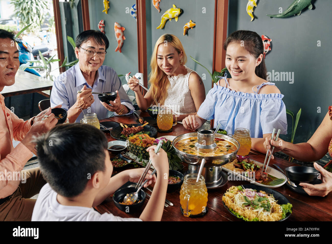 Grand heureux famille vietnamienne de manger des plats savoureux de la cuisine asiatique à grande table in restaurant Banque D'Images