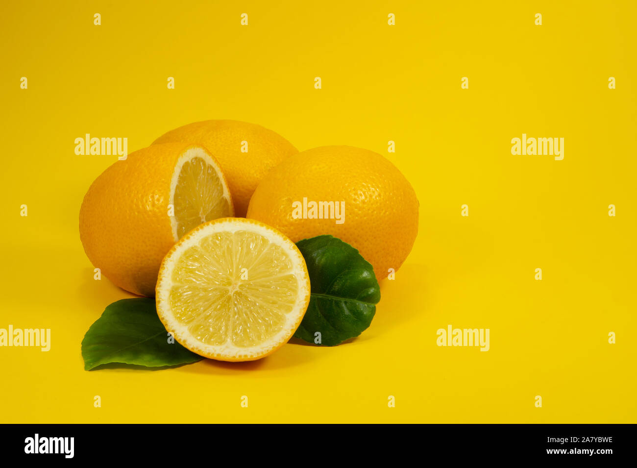 Ensemble et moitié fruits citron mûr avec des feuilles vertes sur fond jaune Banque D'Images