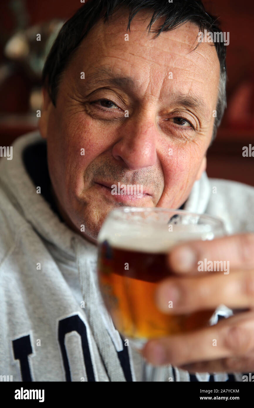 Homme plus âgé buvant du lager dans un verre. Banque D'Images