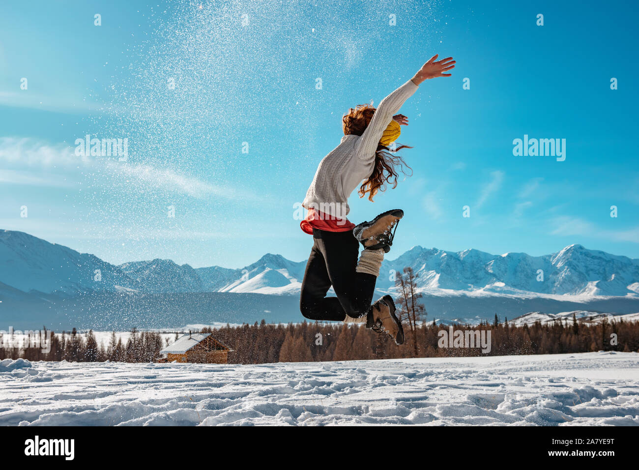 Happy girl les sauts avec contre la neige montagnes aux sommets enneigés. Concept d'hiver Banque D'Images