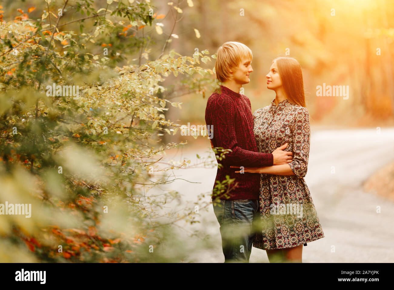 Couple portée dans les vêtements de style automne pulls air de famille qui traverse le paysage d'automne. Feuillage jaune couverte de forêt. Automne marcher à l'extérieur. Deux amoureux en automne parc. Rencontre romantique Banque D'Images
