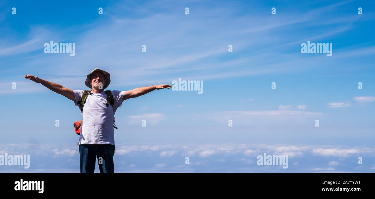 Senior homme debout et profiter de la partie supérieure du monde les bras d'ouverture et souriant - Ciel bleu avec des nuages en fond - concept d'âge aucune limite d'un Banque D'Images