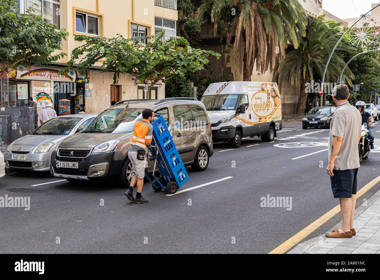 Livraison d'eau embouteillée man pushing trolley chargé avec des caisses sur une rue de Santa Cruz de Tenerife, Canaries, Espagne Banque D'Images