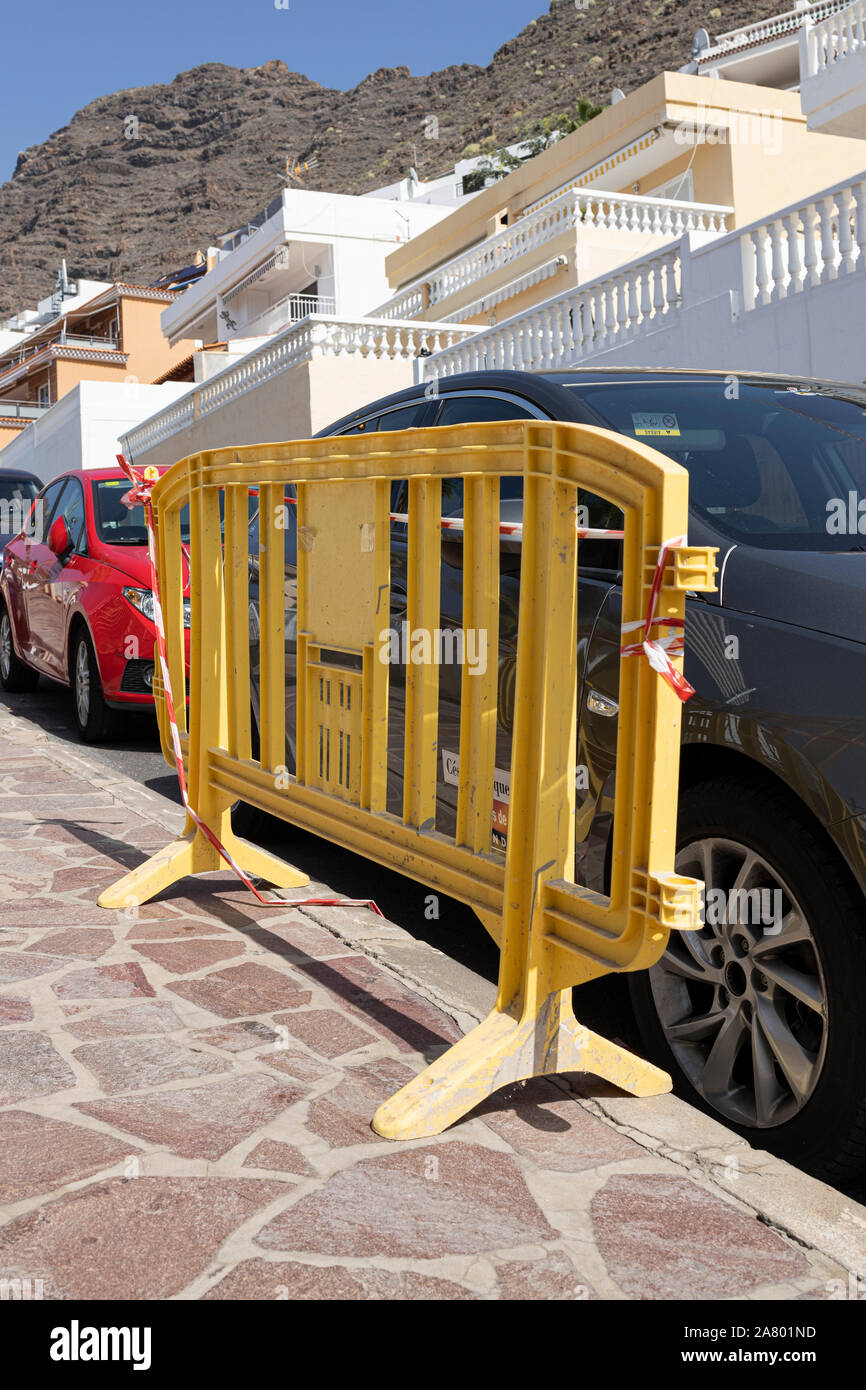 Barrière en plastique jaune sur sentier par des voitures en stationnement à Los Gigantes, Tenerife, Canaries, Espagne Banque D'Images