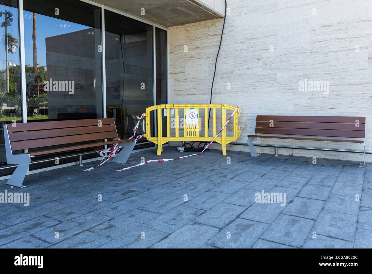 Barrière en plastique jaune dans un coin entre deux bancs à l'extérieur de l'Aéroport de Tenerife Sur Reina Sofia, Tenerife, Canaries, Espagne Banque D'Images