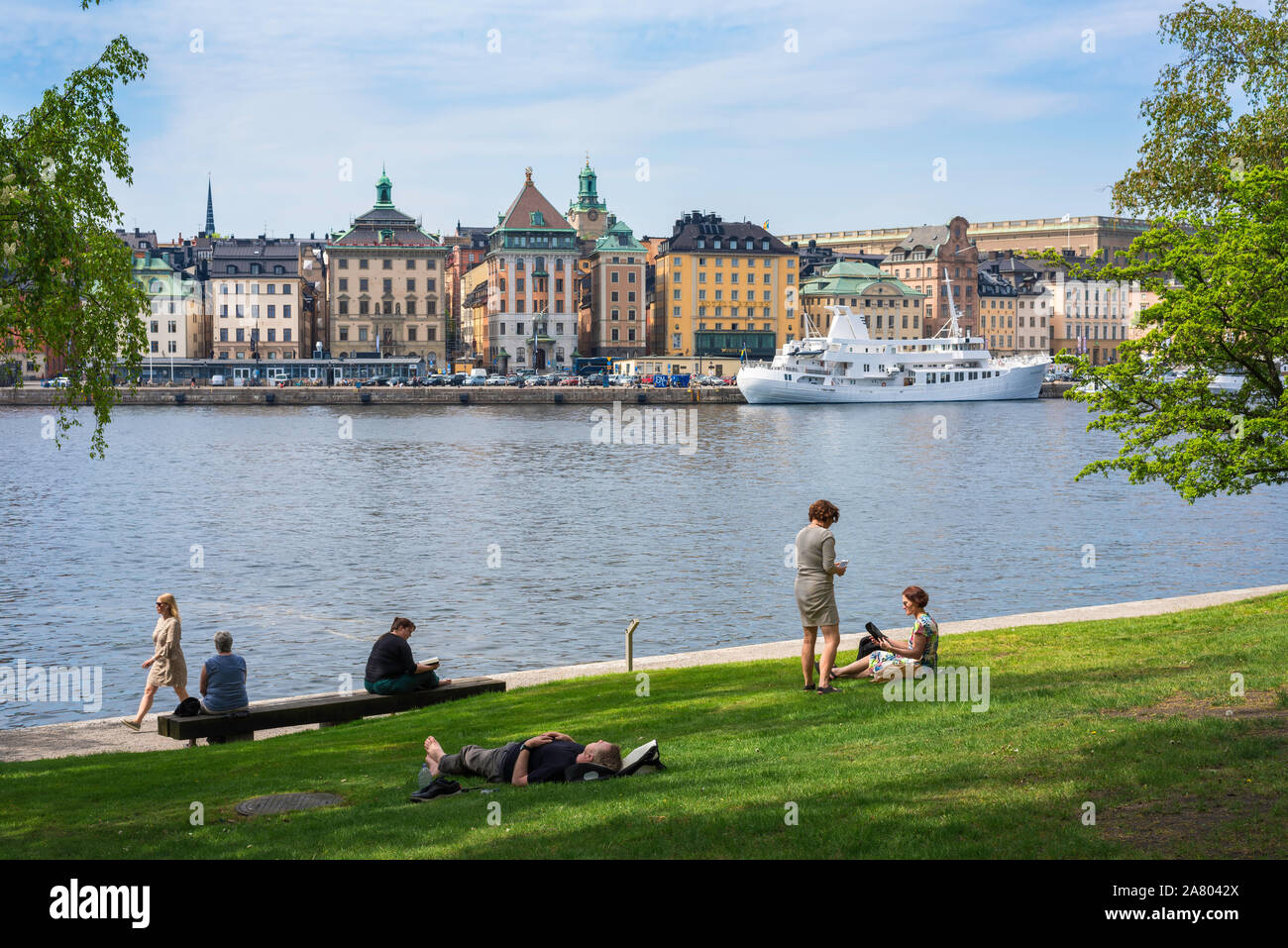 Skeppsholmen Stockholm, vue en été des gens de vous détendre dans le Amiralitetsparken sur l'île de Skeppsholmen avec Gamla Stan dans la distance, Stockholm Banque D'Images