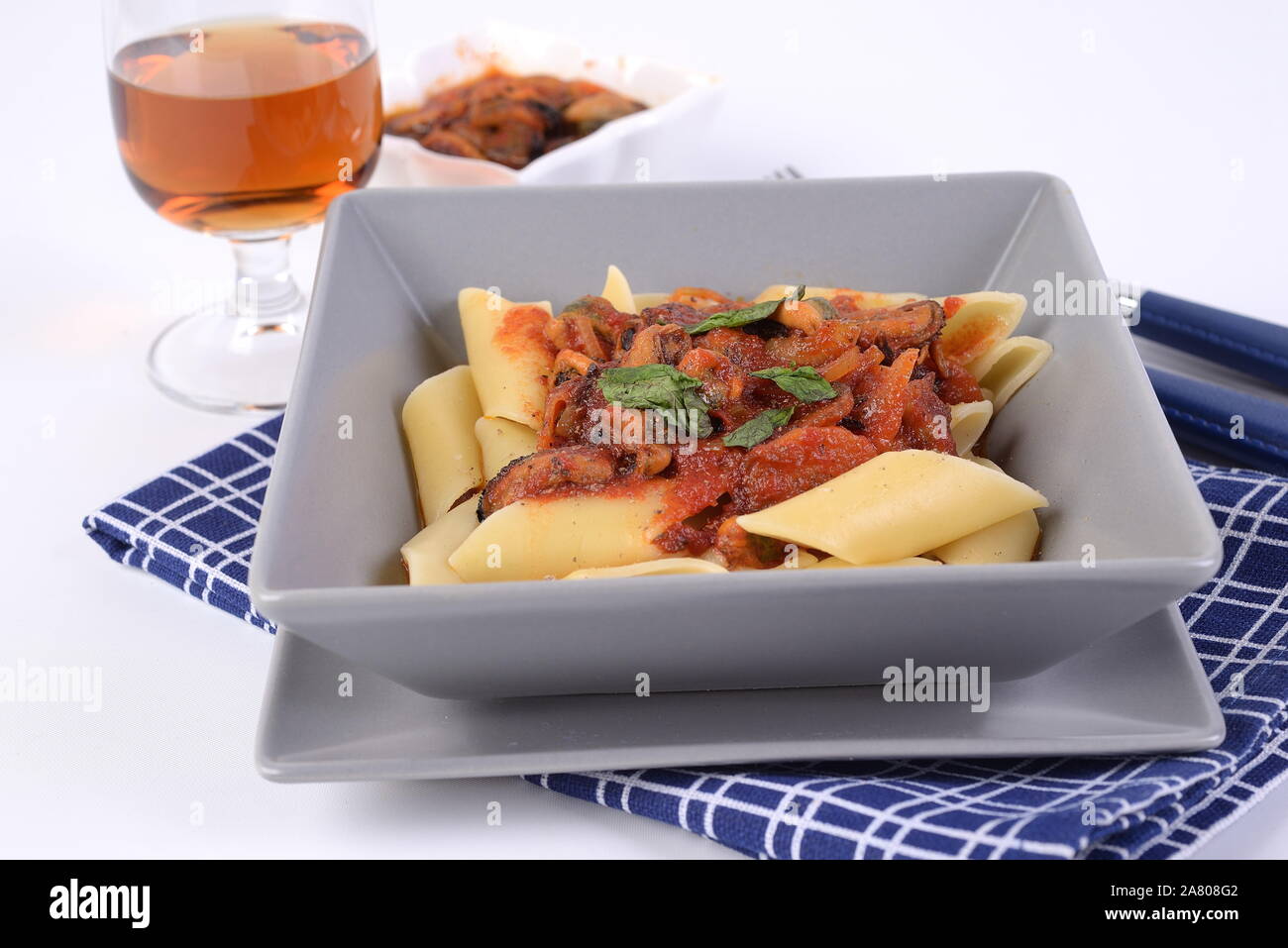 Pâtes Pennoni sauce avec des moules sur la plaque à fond blanc Banque D'Images