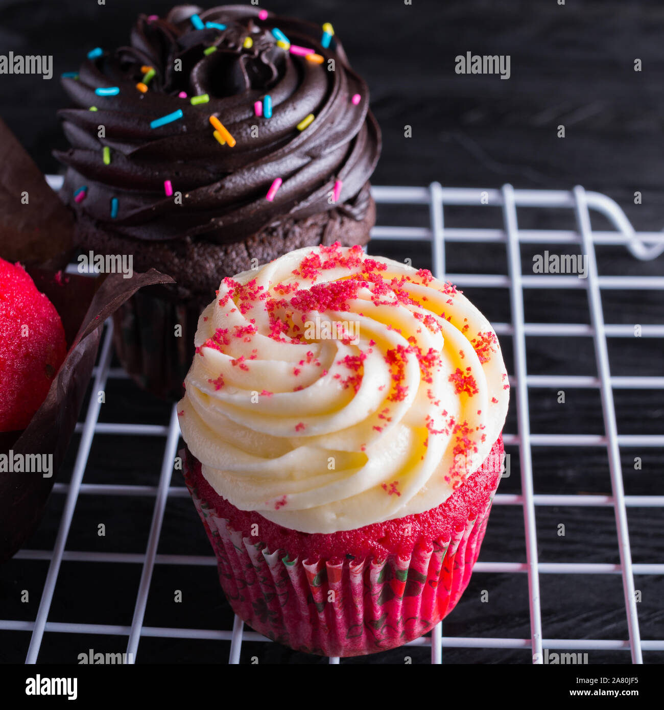 Velours rouge et glace au chocolat blanc et rack cupcake sur fond noir Banque D'Images