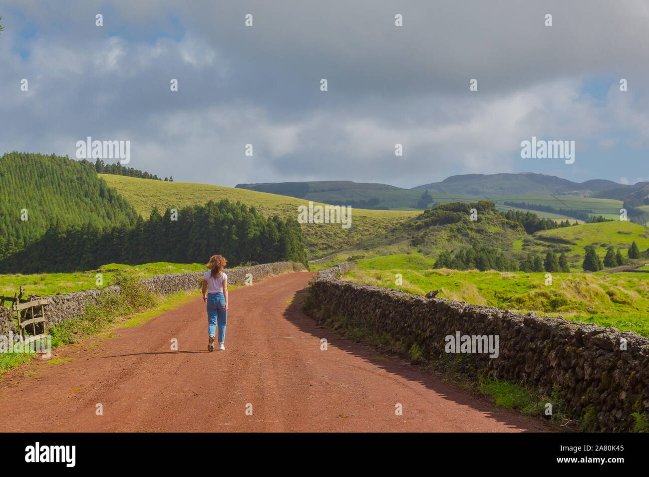 Jeune femme marcher au chemin de campagne. Les champs marqués d'un ciel bleu. Terceira Banque D'Images