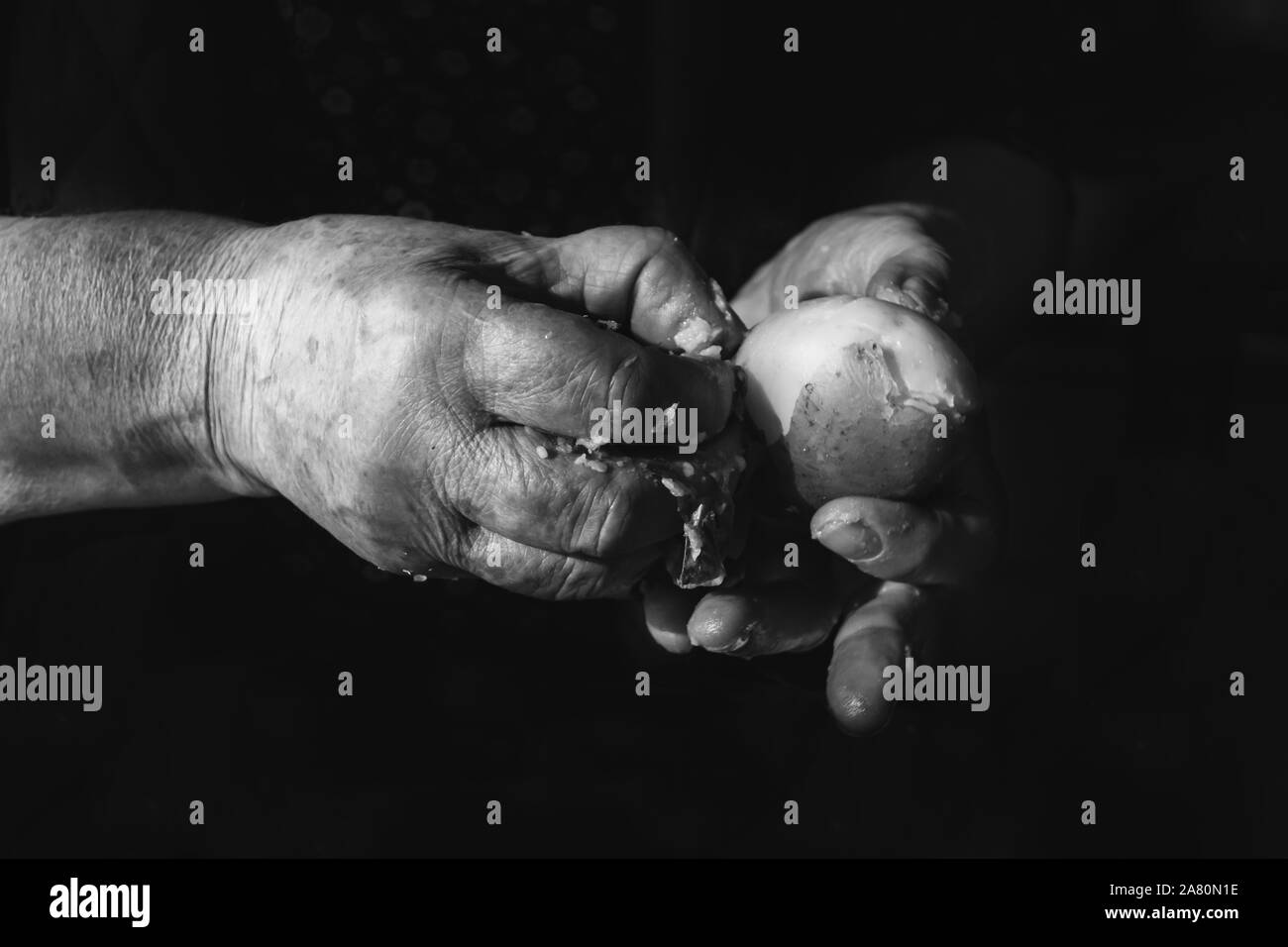Mains de vieille femme un empilage de pommes de terre bouillies. La photographie en noir et blanc. Banque D'Images