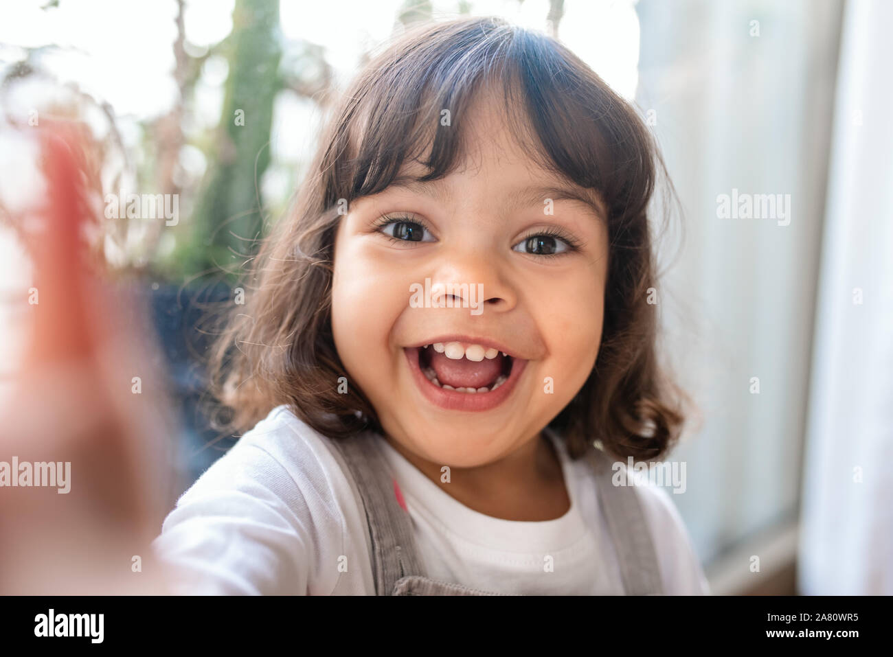 Smiling little girl prenant un tout en jouant à la maison selfies Banque D'Images