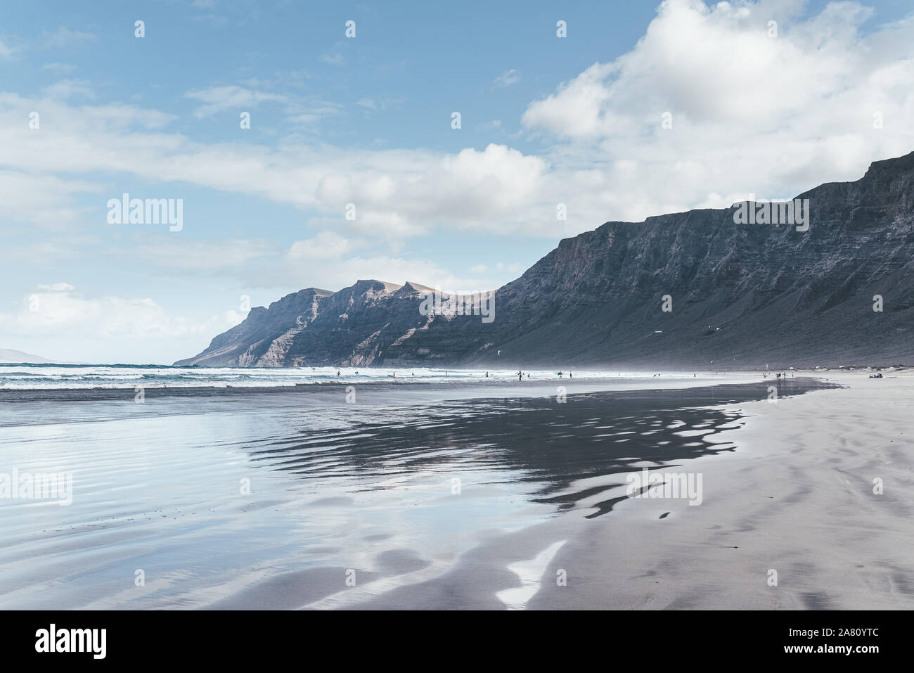 Reflets dans le sable humide et Playa de Famara beach sur Lanzarote, Canaries, contre les montagnes, océan et ciel bleu Banque D'Images