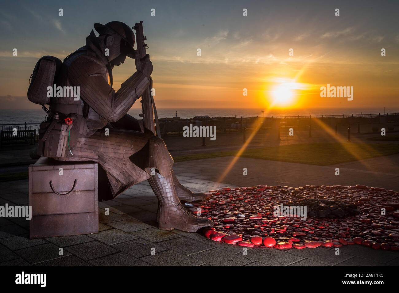 Lever de soleil à la Statue de Tommy le matin du jour du Souvenir à Seaham County Durham. Un service du souvenir aura lieu à la statue de se rappeler les soldats tombés.le mercredi 11 novembre 2015, County Durham, Angleterre. Un hommage à la tombée du jour du Souvenir de l'avant vendredi par le souvenir d'un Fonds du coquelicot géant, créé à l'aide de cailloux de la plage, peints en rouge et le mit aux pieds du 1101 (aka Tommy) statue, un neuf et demi pied sculpture d'un soldat fatigué par Ray Lonsdale.lever de soleil à la Statue de Tommy le matin du jour du Souvenir à Seaham County Durham. Un service Banque D'Images